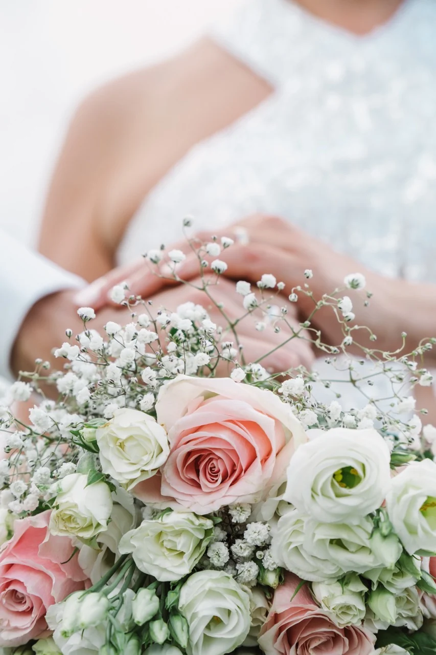 Un bouquet de fleurs blanches et roses dans les mains de la mariée